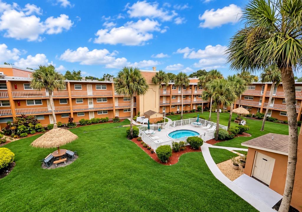 An elevated view of a multi-story apartment complex courtyard featuring a pool and palm trees — 12760 INDIAN ROCKS ROAD UNIT 555, LARGO, FL