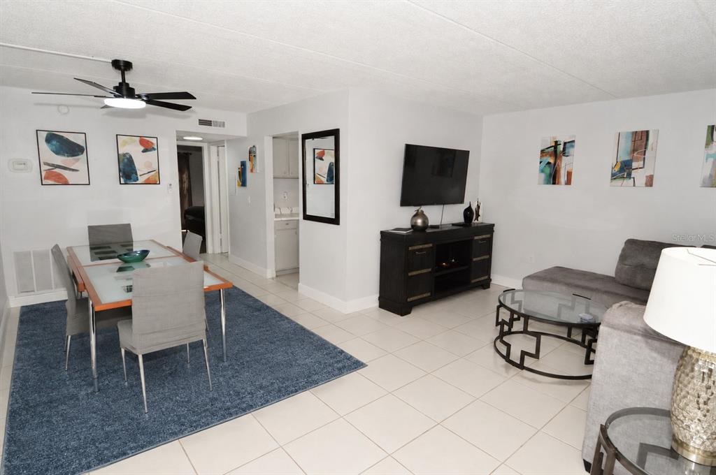 An open-concept living and dining area features tile flooring, a ceiling fan, and modern furniture — 12760 INDIAN ROCKS ROAD UNIT 555, LARGO, FL