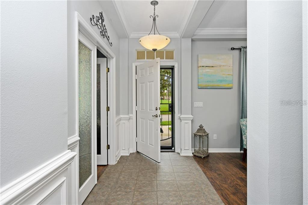 An entryway features tile flooring, white wainscoting, a pendant light, and an open front door — 6971 NOBLETON DRIVE, WINDERMERE, FL