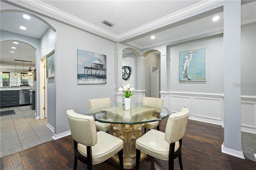 A dining area features a glass-topped table, four cream chairs, and artwork on gray walls — 6971 NOBLETON DRIVE, WINDERMERE, FL