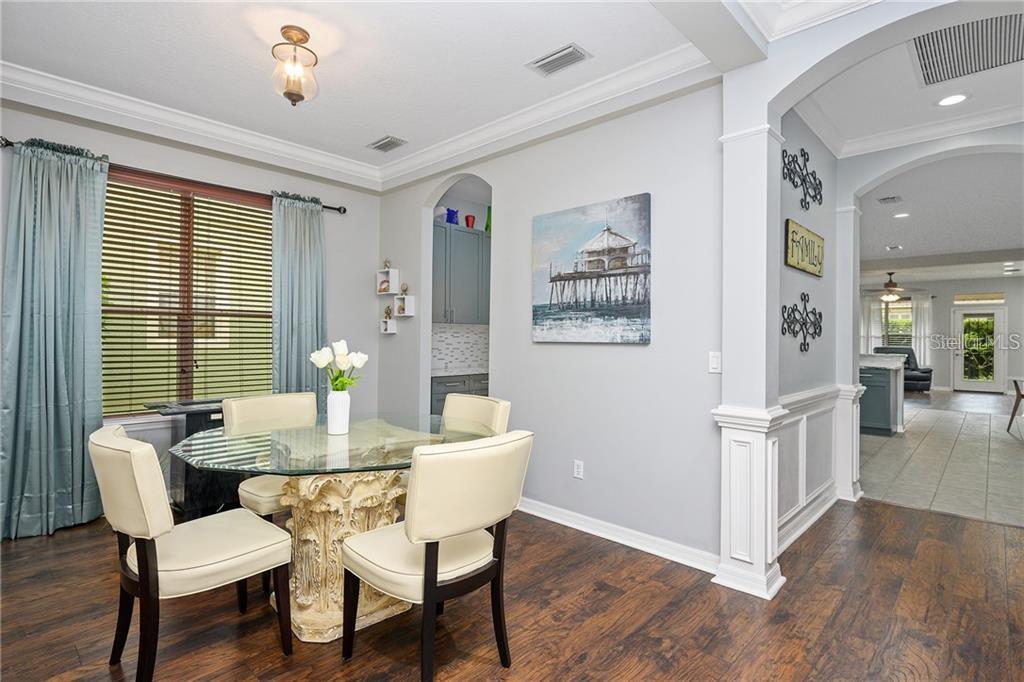 A dining area with a glass-topped table, four chairs, and a view into the kitchen — 6971 NOBLETON DRIVE, WINDERMERE, FL