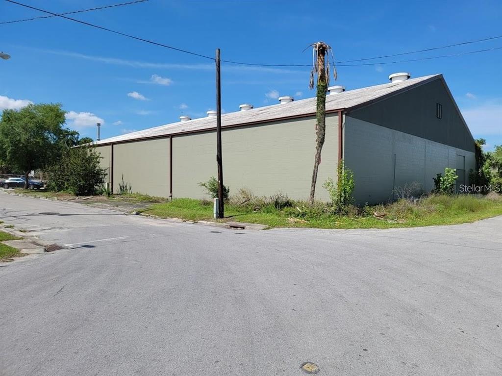 A large, light green industrial warehouse building stands on a corner lot with a palm tree — 530 NW 1ST AVENUE, OCALA, FL