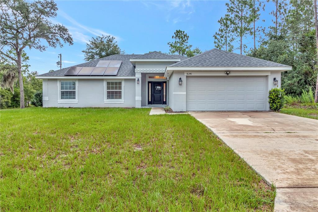 A single-story house with a gray exterior, a two-car garage, and solar panels on the roof — 8241 SW 132 LOOP, OCALA, FL
