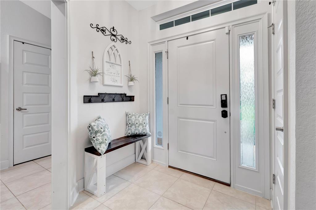 A bright entryway features a white front door, tiled floors, and a wooden bench — 8241 SW 132 LOOP, OCALA, FL