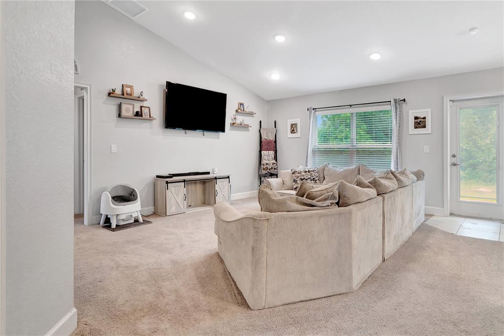 A living room features a large sectional sofa, a wall-mounted television, and a glass door — 8241 SW 132 LOOP, OCALA, FL
