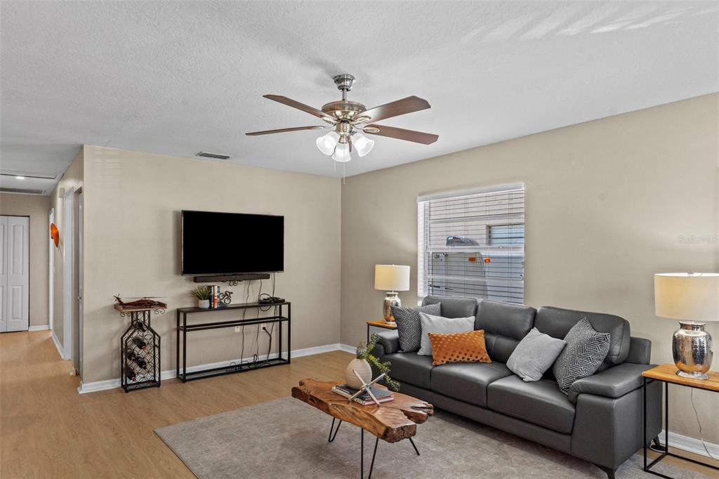 A living room features a grey sofa, a wood coffee table, and a ceiling fan — 7610 S SHERRILL STREET, TAMPA, FL