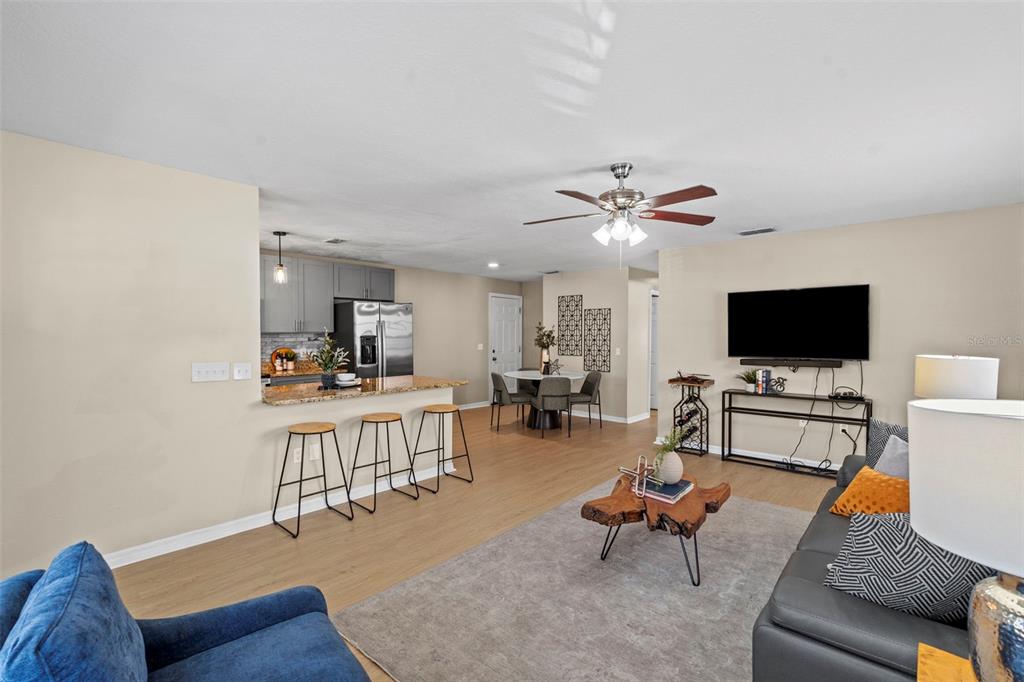 An open-concept living room and kitchen featuring light wood flooring and a breakfast bar — 7610 S SHERRILL STREET, TAMPA, FL