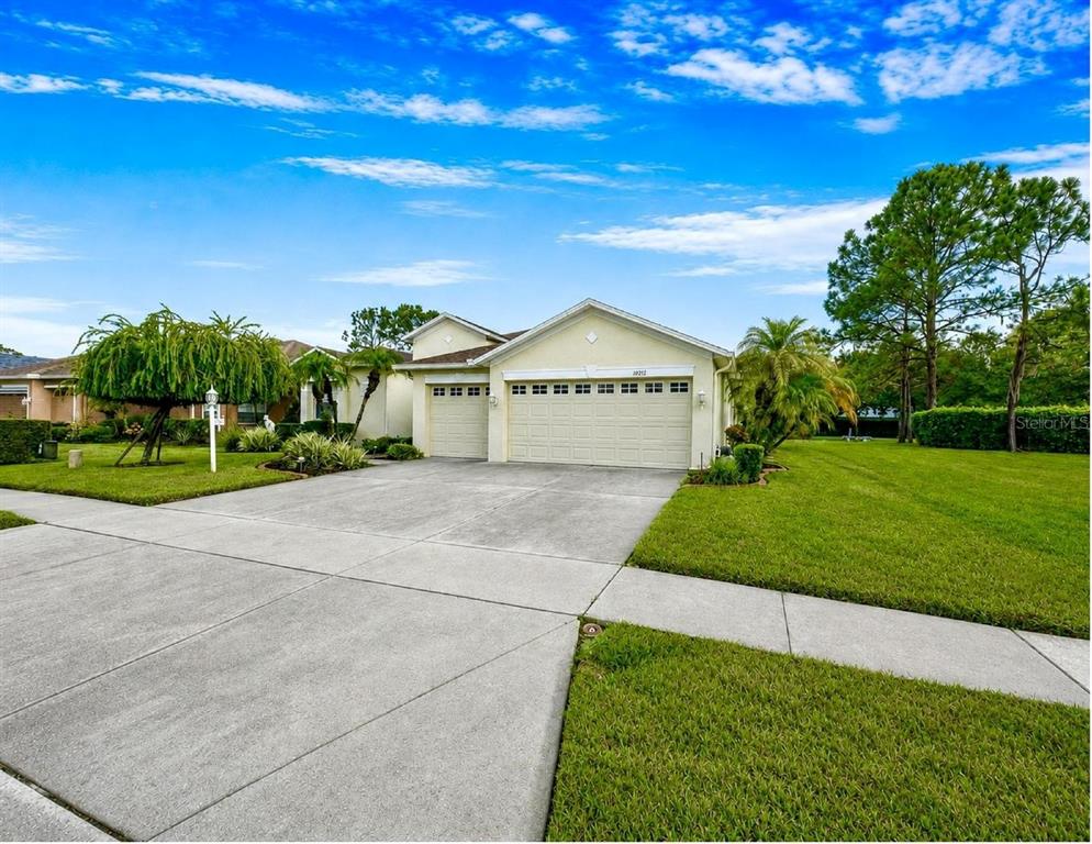 A single-story house with a beige exterior, a three-car garage, and a concrete driveway — 10924 RAIN HOLLOW COURT, TRINITY, FL