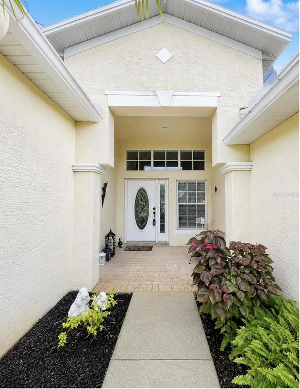 A paved walkway leads to the front entrance of a house with a white door — 10924 RAIN HOLLOW COURT, TRINITY, FL
