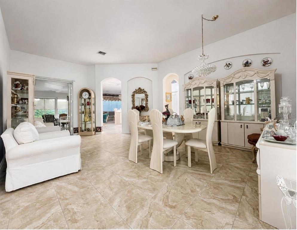 A dining room with a white table, chairs, and two large china cabinets on tile floors — 10924 RAIN HOLLOW COURT, TRINITY, FL