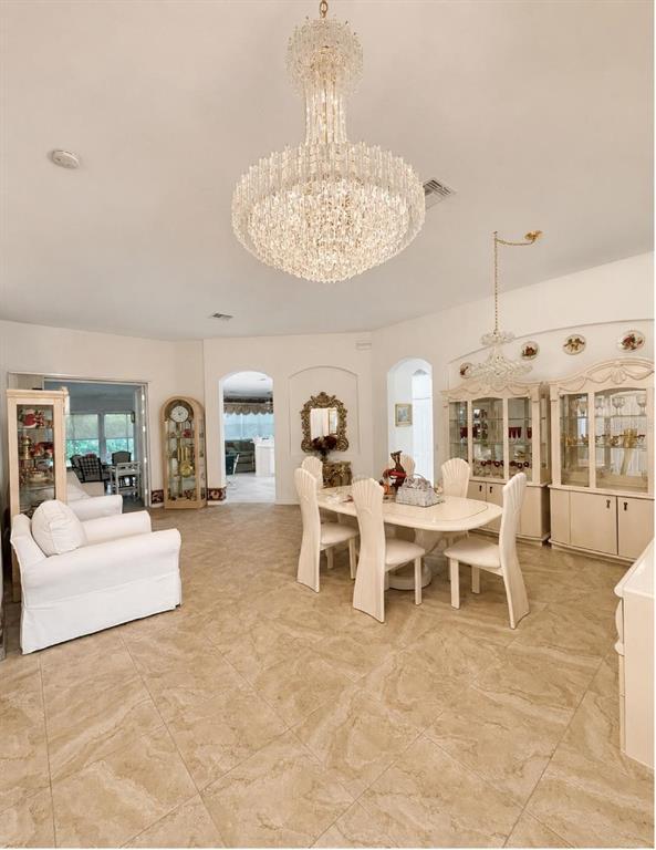 A dining room features a large crystal chandelier, tile flooring, and white furniture — 10924 RAIN HOLLOW COURT, TRINITY, FL