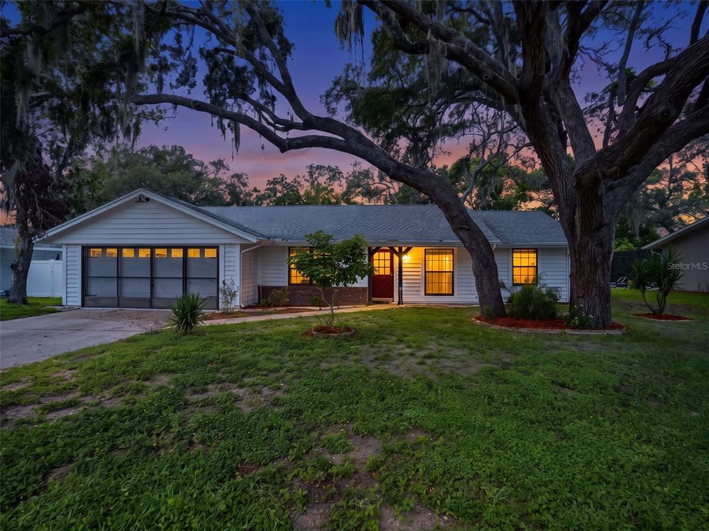 A single-story house with a garage and large trees at dusk — 1139 DESMOND AVENUE, SPRING HILL, FL