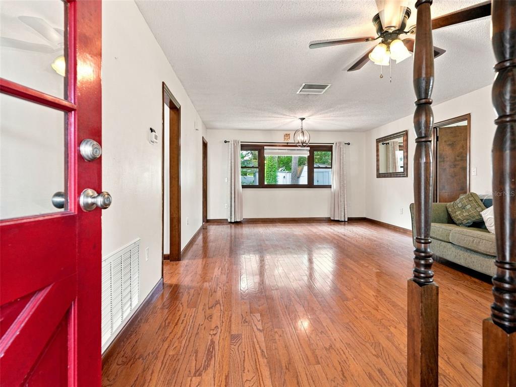 A living room with hardwood floors, a ceiling fan, and a view through a large window — 1139 DESMOND AVENUE, SPRING HILL, FL