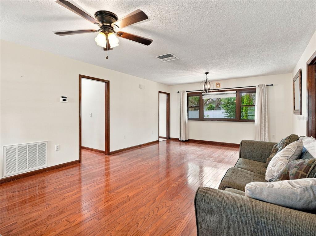 A living room with hardwood floors, a ceiling fan, and a sofa facing a window — 1139 DESMOND AVENUE, SPRING HILL, FL