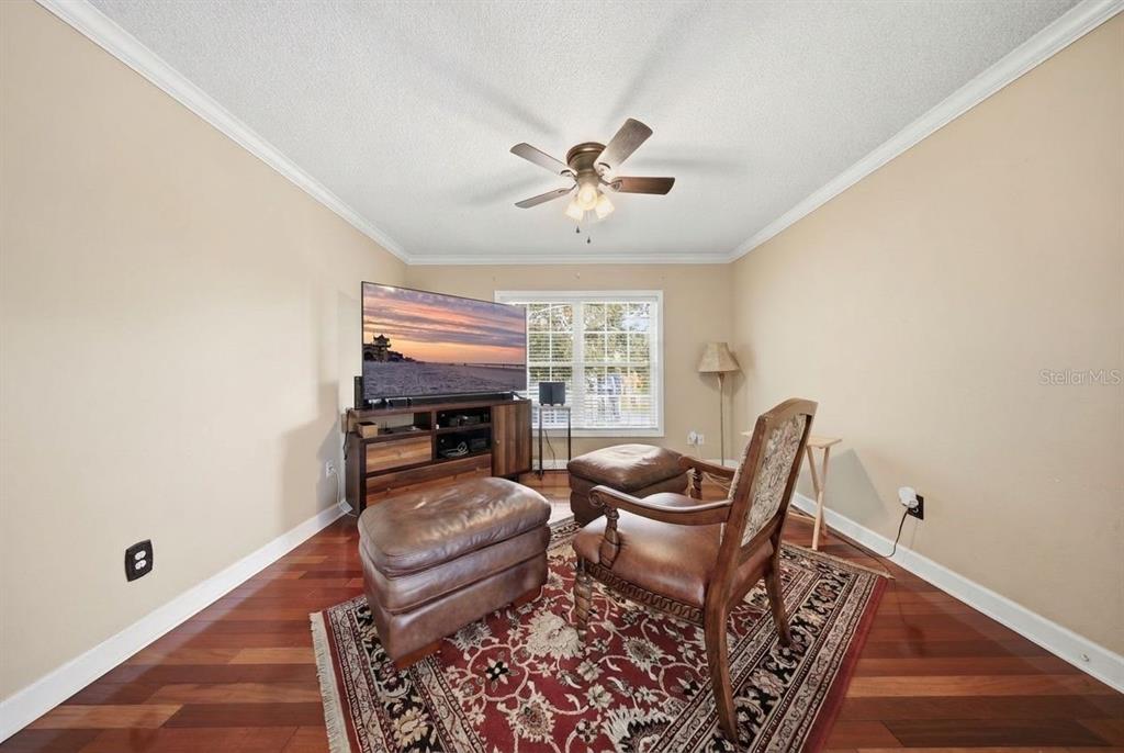 A living room with hardwood floors, a ceiling fan, a television, and a leather chair — 4890 CONWAY ROAD UNIT 66, ORLANDO, FL