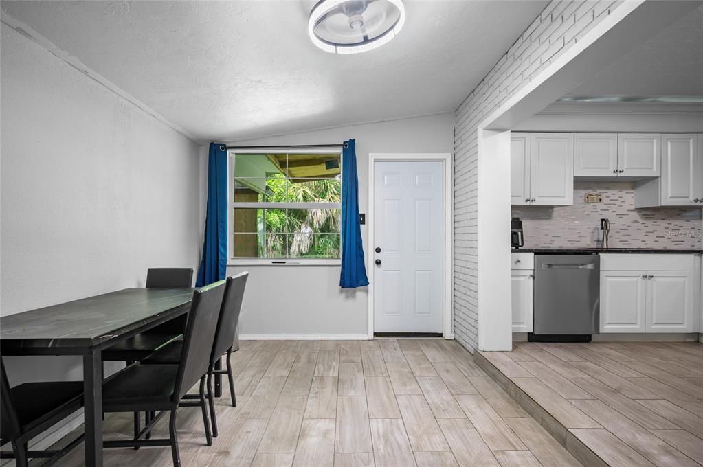 A dining area with a table and chairs next to a kitchen with white cabinets — 340 TIMBRUCE LANE NW, PORT CHARLOTTE, FL