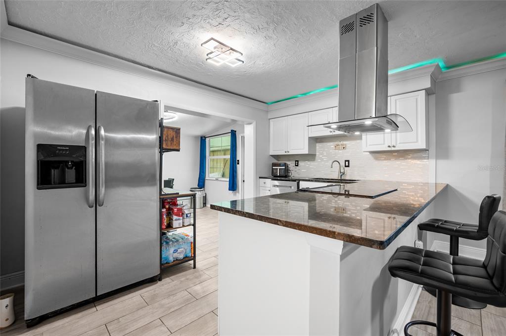 A kitchen with stainless steel appliances, white cabinets, granite countertops, and a breakfast bar — 340 TIMBRUCE LANE NW, PORT CHARLOTTE, FL