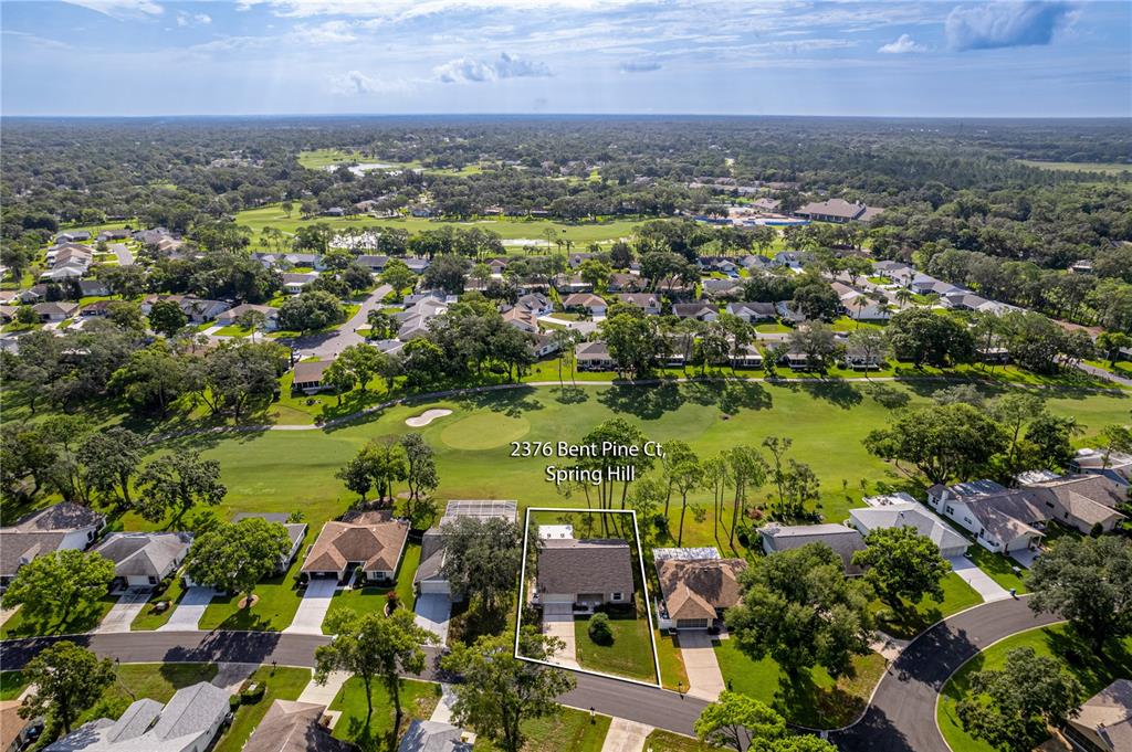 An aerial view shows a single-family house situated on a golf course in a neighborhood — 2376 BENT PINE COURT, SPRING HILL, FL