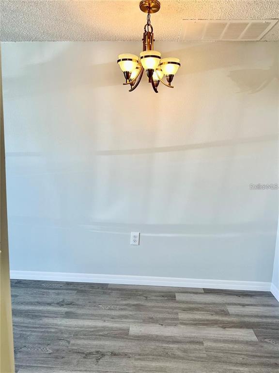 A dining area features light gray walls, a modern chandelier, and wood-look laminate flooring — 4930 GETNER STREET UNIT 0, NEW PORT RICHEY, FL