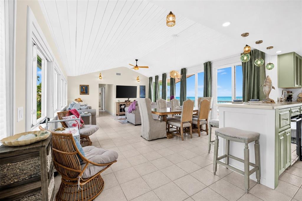 An open-concept living and dining area features tile floors, a vaulted ceiling, and ocean views — 921 N ATLANTIC AVENUE, NEW SMYRNA BEACH, FL