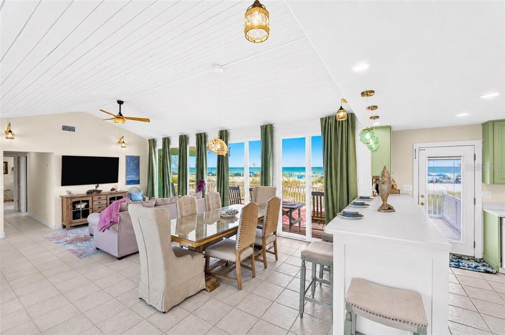 An open-concept living and dining area features tile floors, a vaulted ceiling, and beach views — 921 N ATLANTIC AVENUE, NEW SMYRNA BEACH, FL
