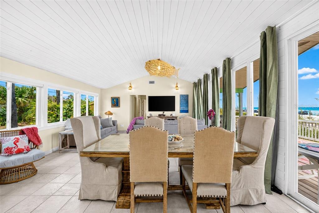 A dining area with a glass-topped table, upholstered chairs, and large windows overlooking the beach — 921 N ATLANTIC AVENUE, NEW SMYRNA BEACH, FL