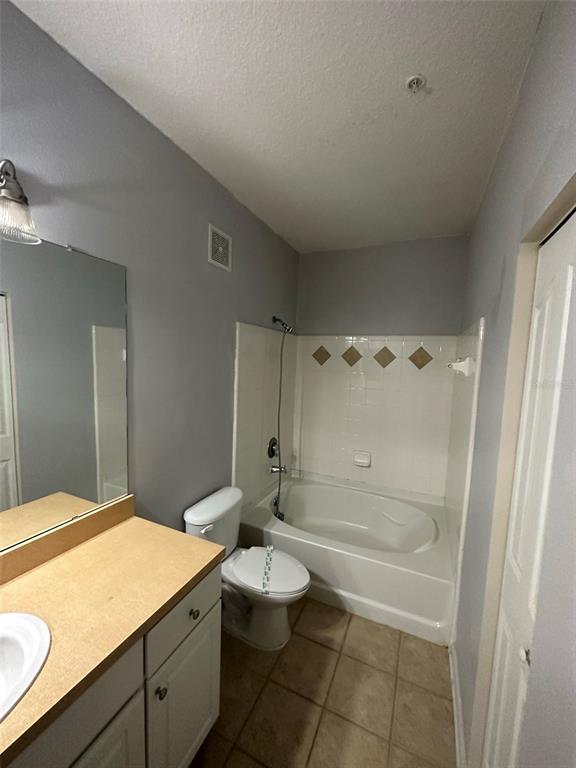 A bathroom features a vanity with a light countertop, a toilet, and a tiled tub-shower — 6005 NEWPORT LANE UNIT 103, ORLANDO, FL