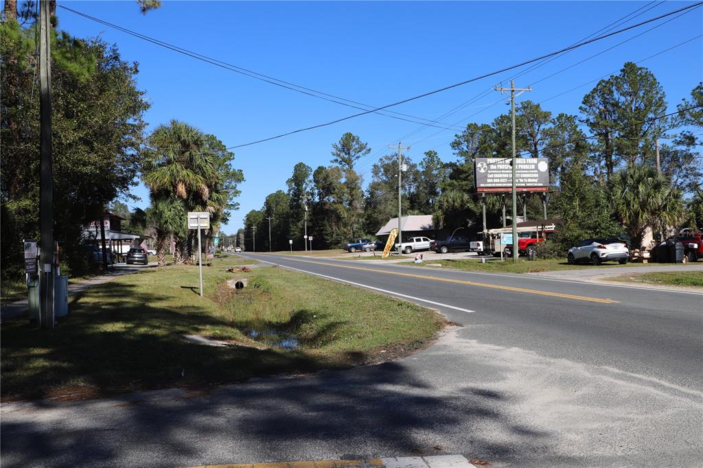 A paved road stretches through a rural area with trees, utility poles, and parked vehicles — 850 N STATE ROAD 21, MELROSE, FL