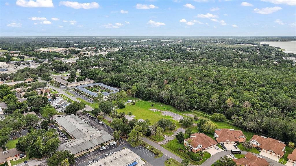 An aerial view shows a residential area with apartment buildings, parking lots, and wooded land — W OAK TERRACE DRIVE, LEESBURG, FL