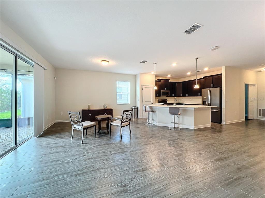 An open-concept kitchen and dining area features dark wood cabinets, a breakfast bar, and tile flooring — 1065 BLACKWOLF RUN RD, DAVENPORT, FL