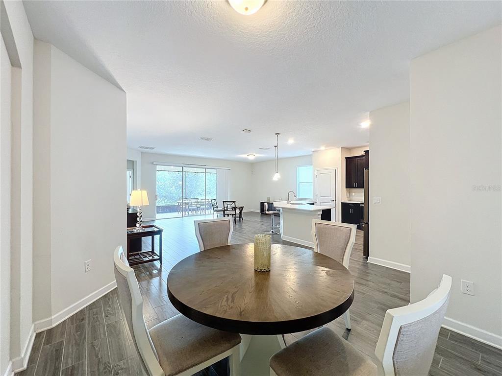 A dining area with a round wooden table opens into a kitchen and living space — 1065 BLACKWOLF RUN RD, DAVENPORT, FL