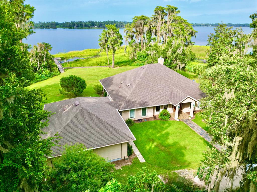 An aerial view of a house with a shingled roof, lawn, and a private dock — 20924 NE 132ND AVENUE, WALDO, FL