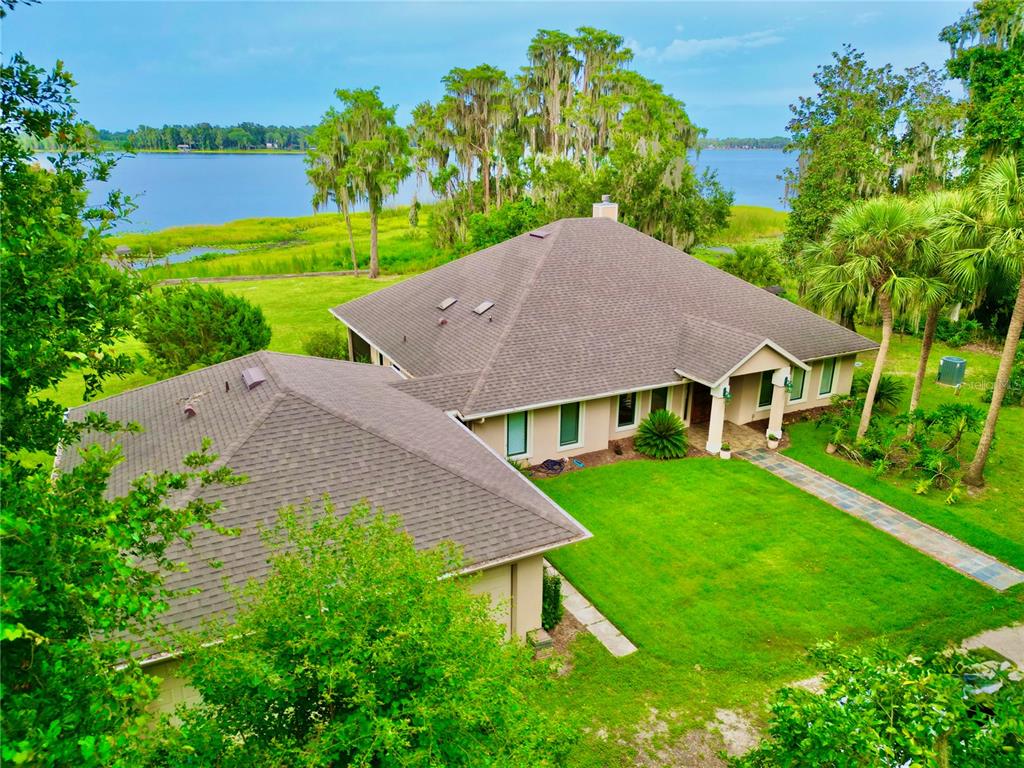 An aerial view of a single-story house with a brown roof overlooking a lake — 20924 NE 132ND AVENUE, WALDO, FL