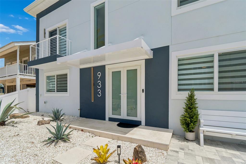 A modern two-story house exterior features a white awning over double glass entry doors — 933 ELDORADO AVENUE, CLEARWATER BEACH, FL