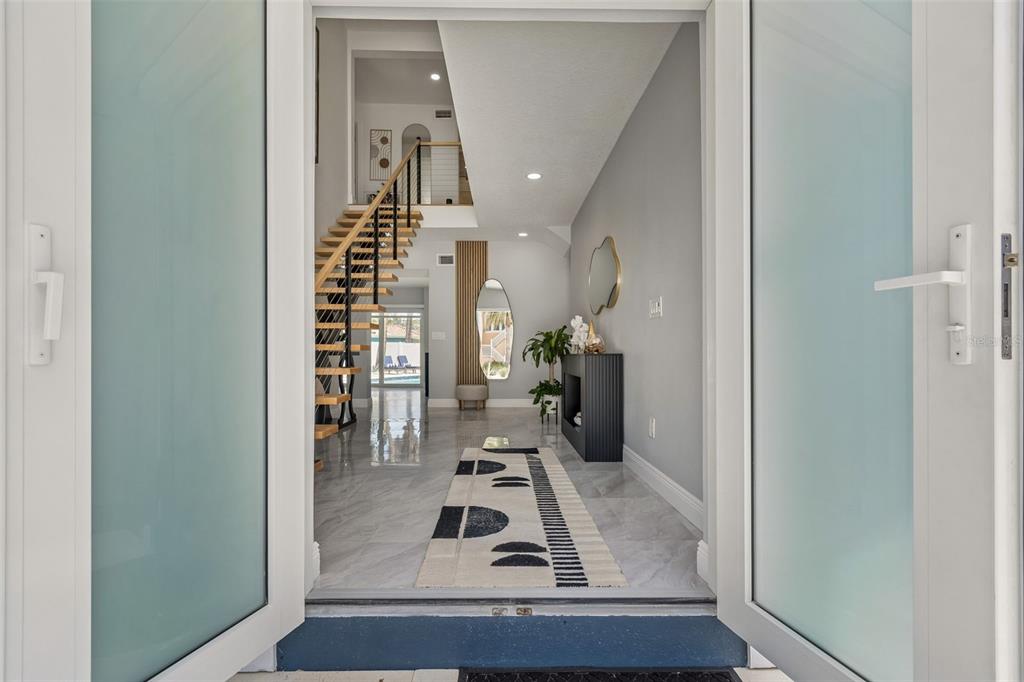 An entryway with a modern staircase, marble-look tile flooring, and a long patterned runner rug — 933 ELDORADO AVENUE, CLEARWATER BEACH, FL