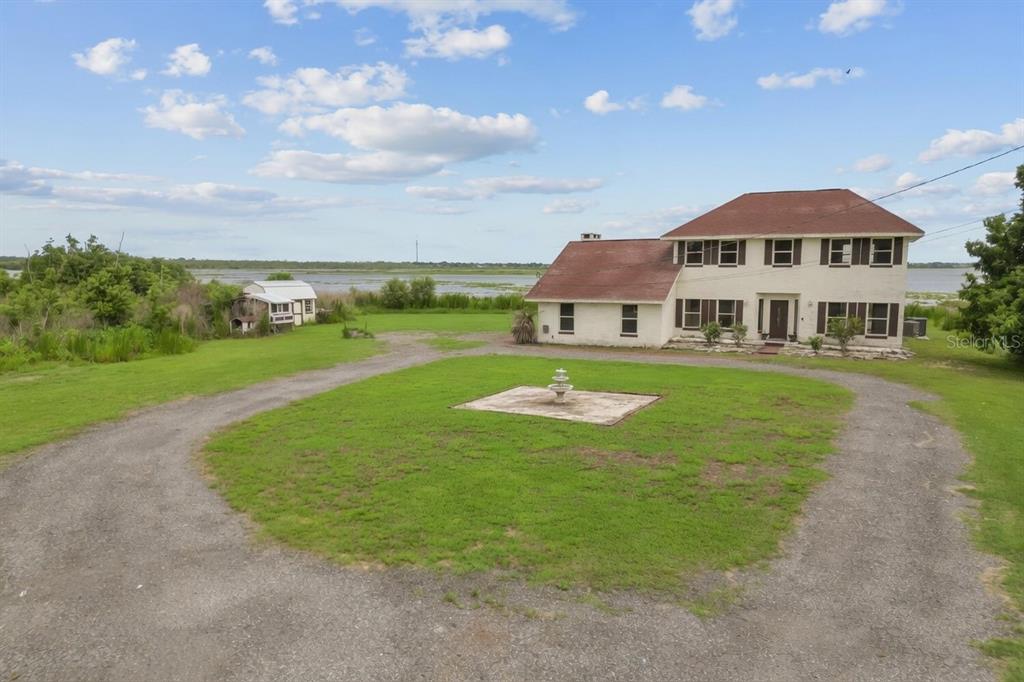 An aerial view shows a house with a red roof situated near a large lake — 3101 LAKE LOWERY ROAD, HAINES CITY, FL