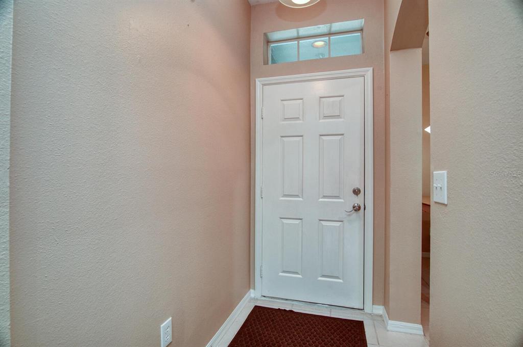 An interior entryway features a white six-panel door, a transom window, and beige walls — 11092 WINDSOR PLACE CIRCLE, TAMPA, FL