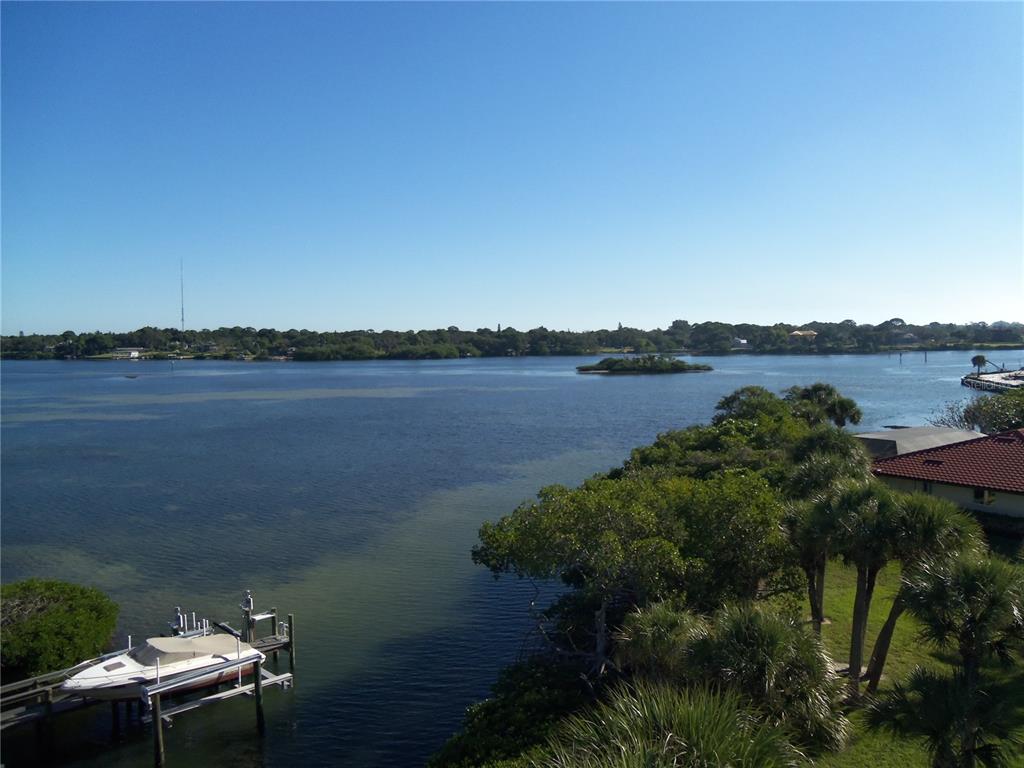An elevated view of a boat docked at a pier overlooking a wide, calm bay — 1210 CASEY KEY ROAD, NOKOMIS, FL