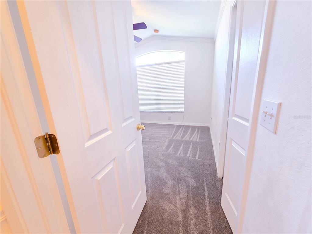 A view through an open doorway into a carpeted bedroom with a ceiling fan — 3549 BEAUMONT LOOP, SPRING HILL, FL