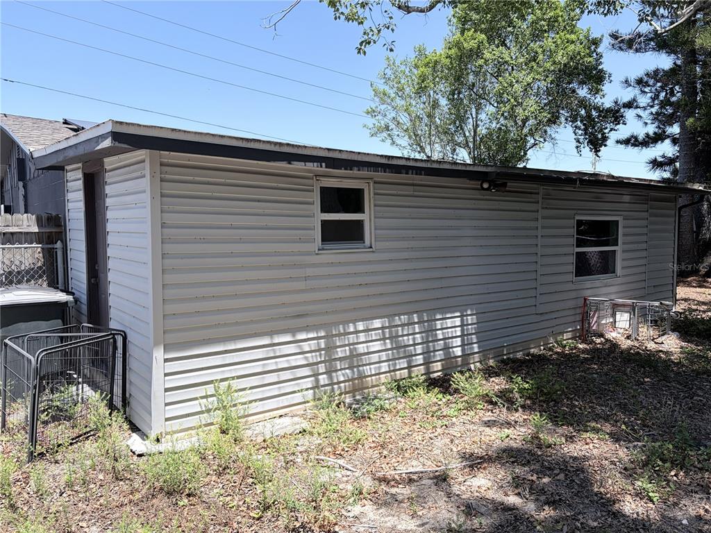 The exterior of a single-story building with light-colored horizontal siding and two windows — 3818 MOOG ROAD, HOLIDAY, FL