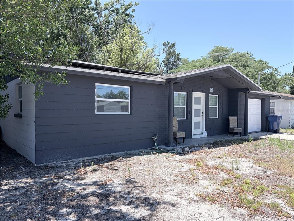 A single-story house with dark gray siding, a brick facade, and a front-facing garage — 3818 MOOG ROAD, HOLIDAY, FL