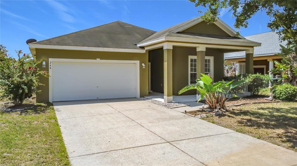 A single-story house with a two-car garage, olive-green siding, and a covered front porch — 240 JAMES CIRCLE, LAKE ALFRED, FL