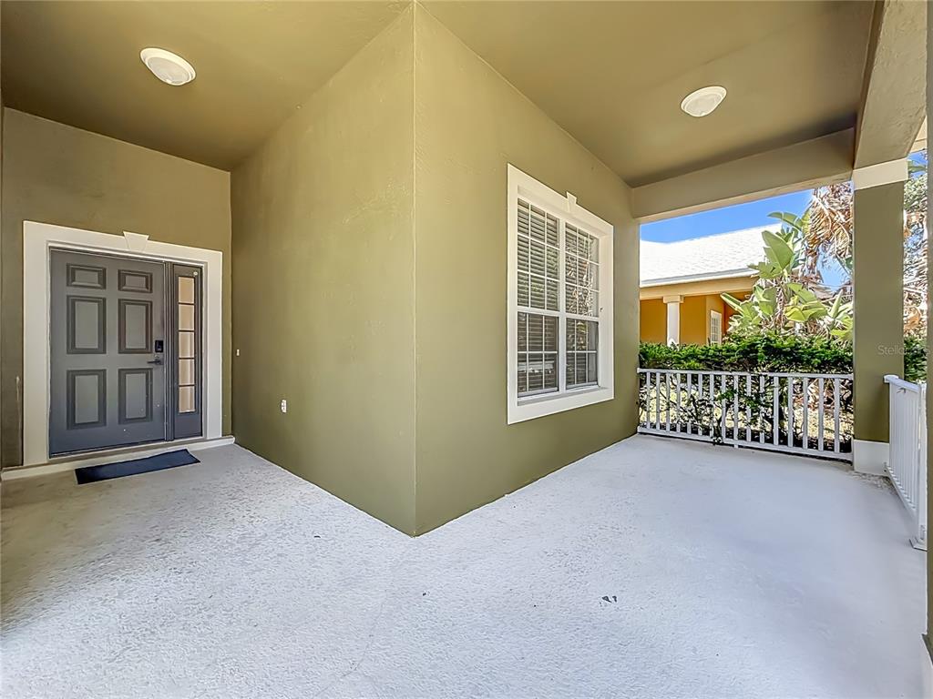 A covered porch features a gray front door, a large window, and a white railing — 240 JAMES CIRCLE, LAKE ALFRED, FL