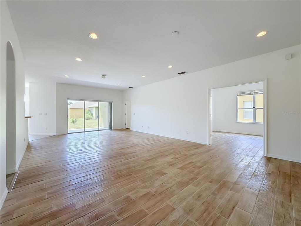 An open living area features wood-look tile flooring, recessed lighting, and a sliding glass door — 240 JAMES CIRCLE, LAKE ALFRED, FL
