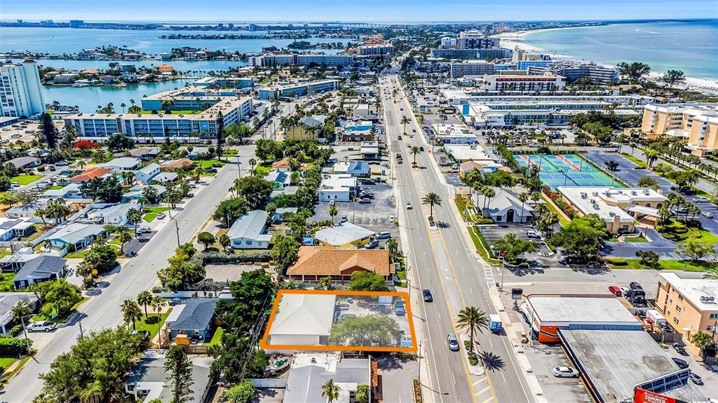 An aerial view shows a commercial property with a white roof highlighted by an orange border — 6655 GULF BOULEVARD, ST PETE BEACH, FL
