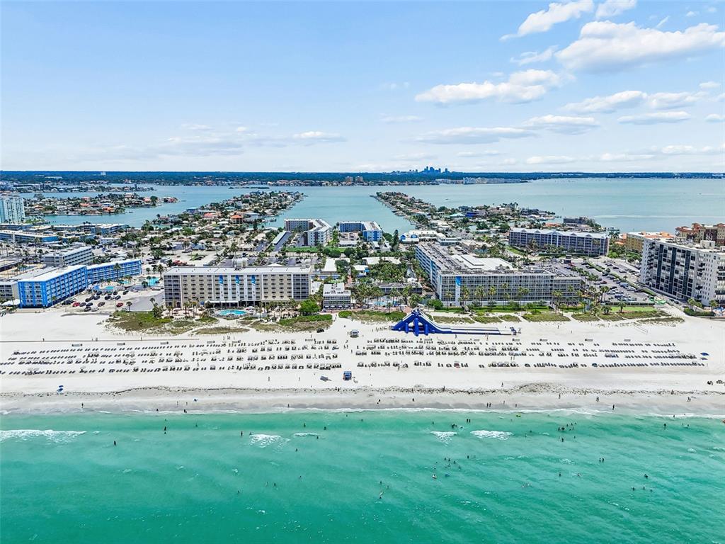An aerial view shows a beach with large apartment buildings and a blue water slide — 5500 GULF BOULEVARD UNIT 6241, ST PETE BEACH, FL