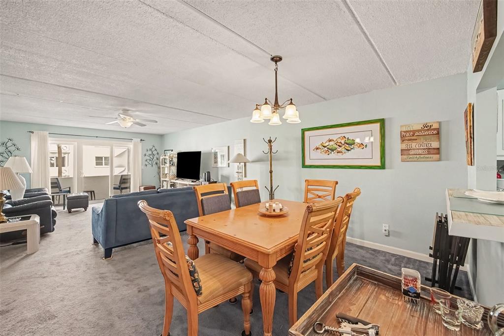 A dining area with a wooden table and chairs sits in front of a living room — 1926 OCEAN SHORE BOULEVARD UNIT 210, ORMOND BEACH, FL