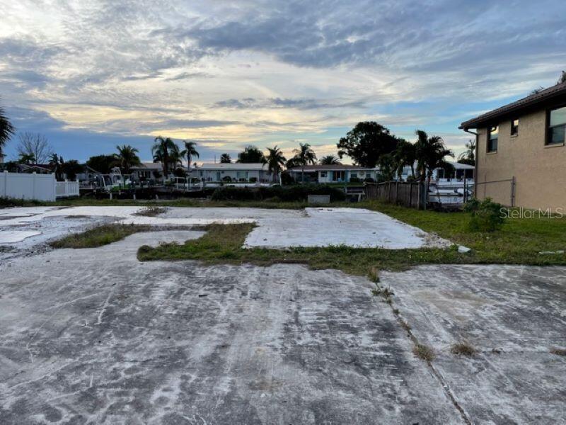 A vacant residential lot features a concrete foundation slab overlooking a canal with palm trees — 5008 ENSIGN LOOP, NEW PORT RICHEY, FL