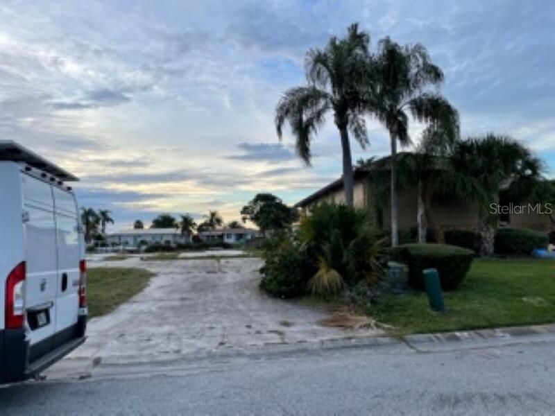 A vacant lot with a concrete driveway sits next to a house and palm trees — 5008 ENSIGN LOOP, NEW PORT RICHEY, FL