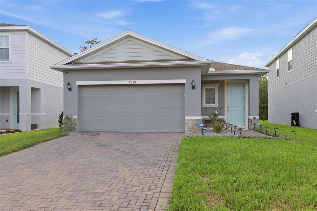 A single-story house with a gray exterior, a two-car garage, and a light blue front door — 7068 LANIER FALLS ROAD, DELAND, FL
